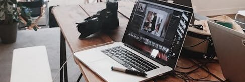 A bright, modern workspace featuring laptops, a camera, and a drawing tablet in an indoor office.